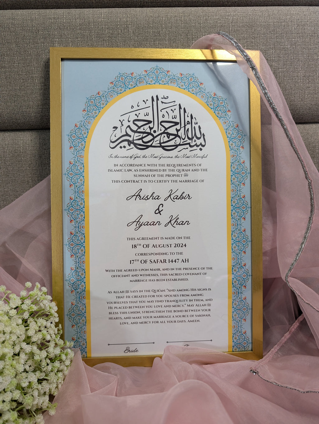 Decorative wedding invitation framed with gold border on a pink fabric background